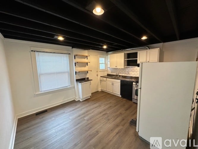A kitchen with white cabinets and a wooden floor.