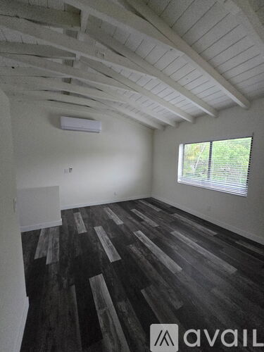 A room with wooden flooring and a window with blinds.