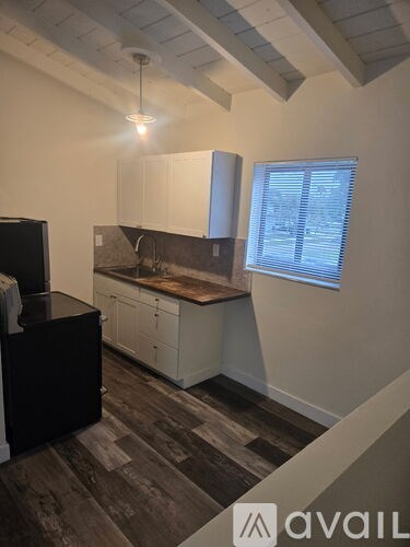 A kitchen with dark wood flooring and white cabinets.