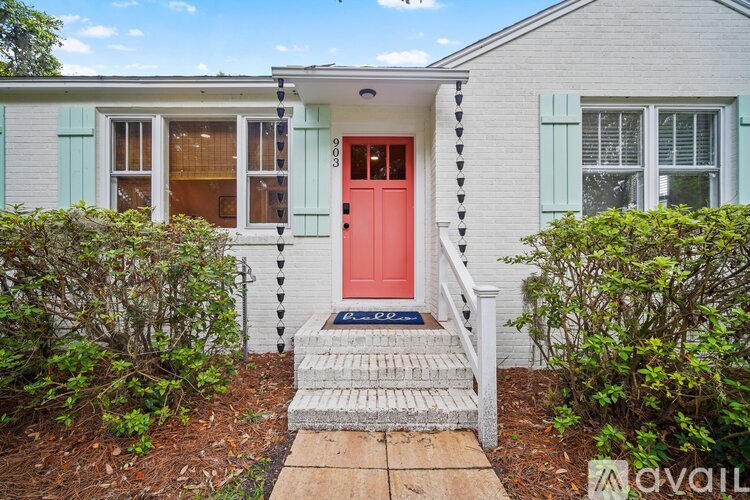 A house with a red door and a wooden walkway leading to it.