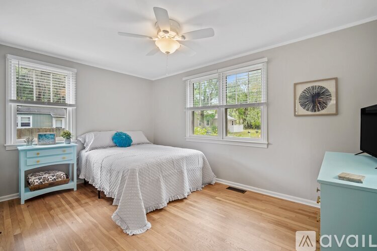 A bedroom with a bed, a dresser, and a ceiling fan.