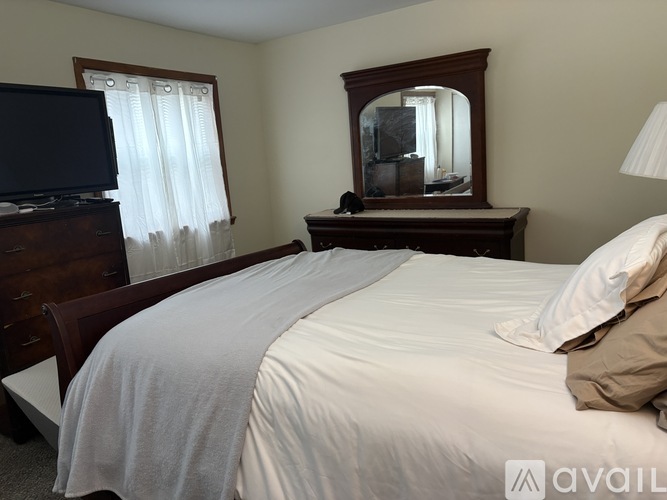 A bedroom with a large bed, a dresser, and a mirror.