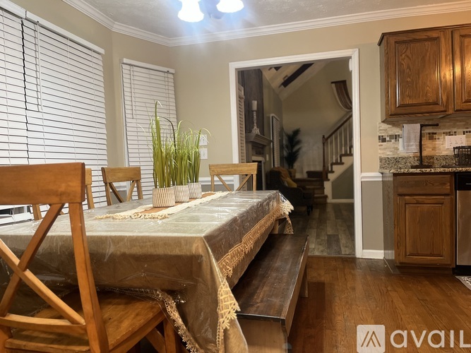 A bedroom with a bed, wooden chairs, and a dining table.