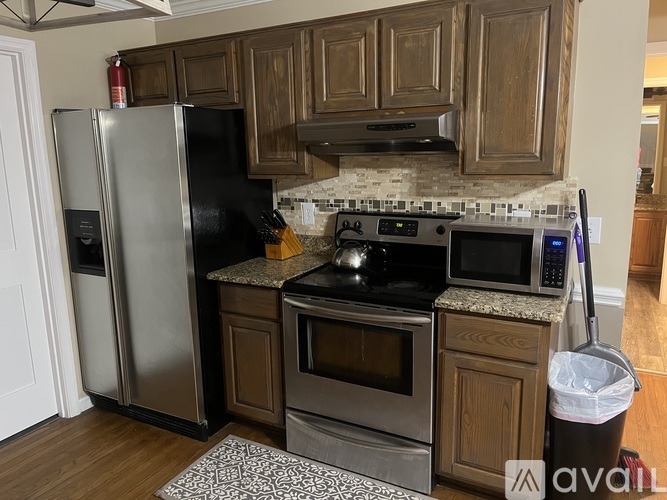 A kitchen with a black refrigerator and stove top oven.