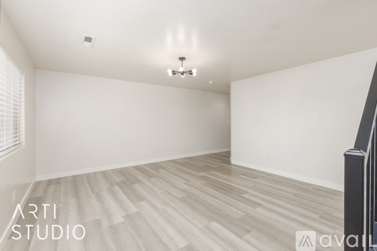 A spacious room with wooden flooring and a chandelier.