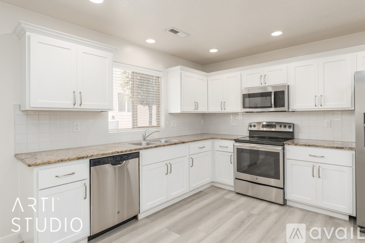 A modern kitchen with white cabinets and stainless steel appliances.