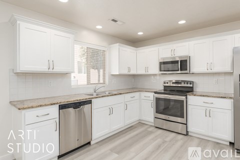 A modern kitchen with white cabinets and stainless steel appliances.