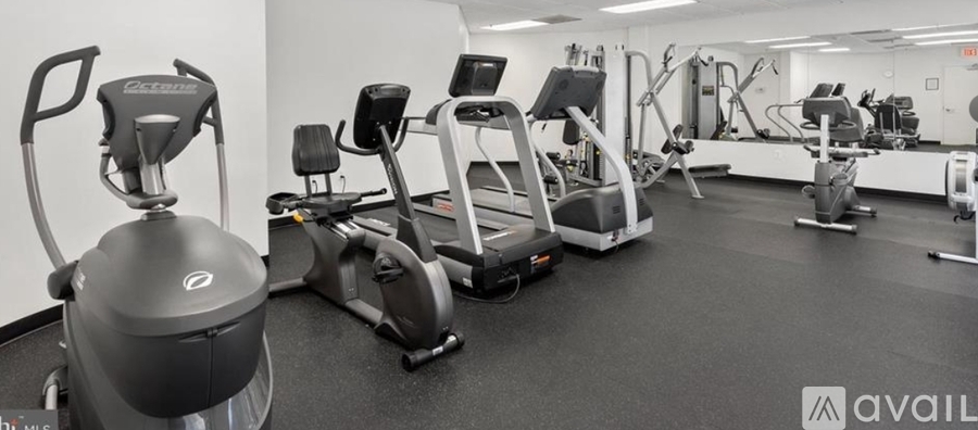 A gym with a variety of exercise equipment including treadmills, stationary bikes, and weight machines.