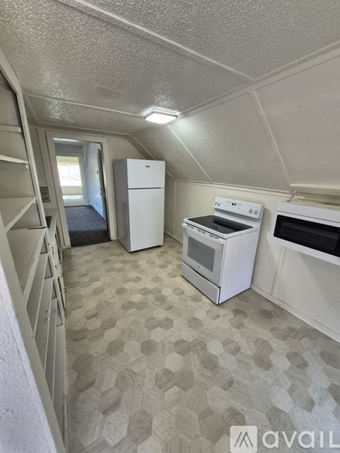 A small kitchen with a white fridge, stove and oven.