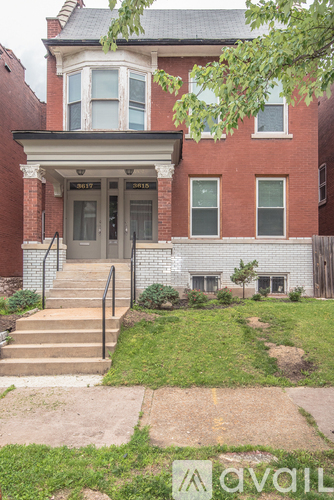 A brick house with a front yard and a tree.
