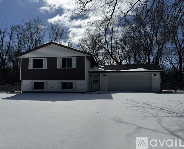 A house with a brown and white exterior is surrounded by snow.