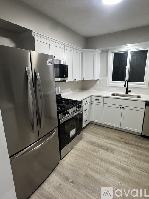 A kitchen with a stainless steel refrigerator and wooden flooring.