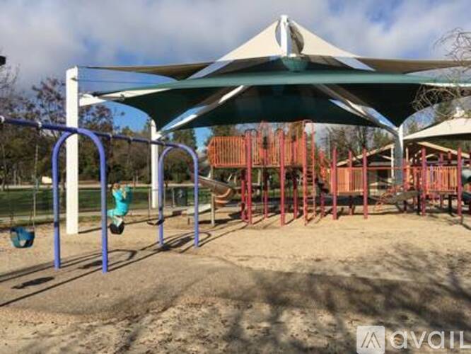 A playground with a swing set and a shaded area.