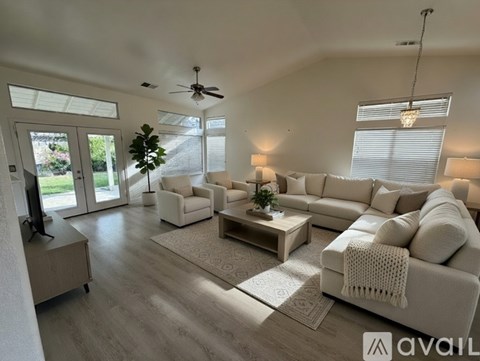 A spacious living room with white furniture and a flat-screen TV.