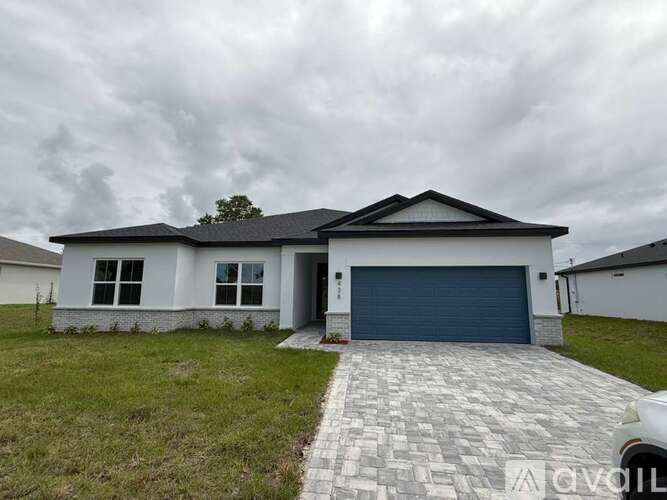 A white house with a grey roof and a blue garage door.