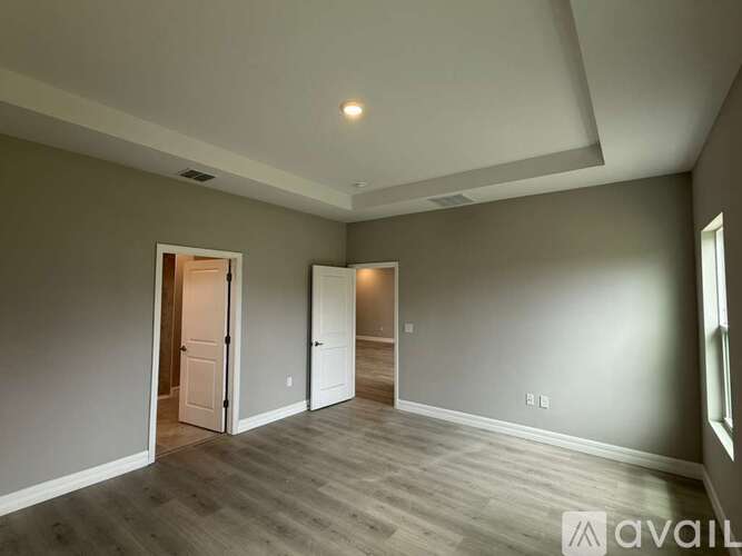 A spacious room with grey walls and wooden flooring.