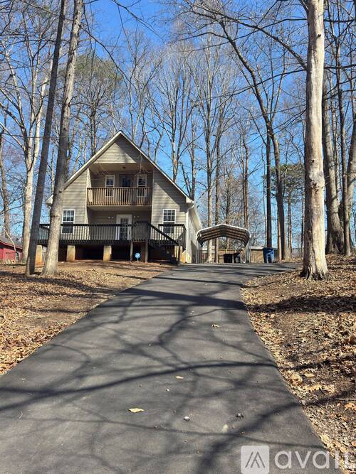 A house with a balcony is surrounded by trees.