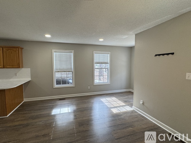 A room with wooden floors and two windows.