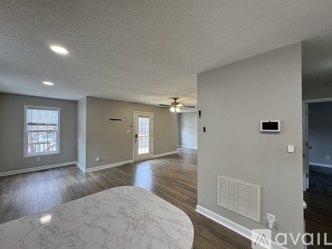 A spacious room with a marble table and wooden floors.