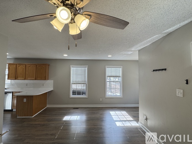 A spacious living room with a ceiling fan and wooden flooring.
