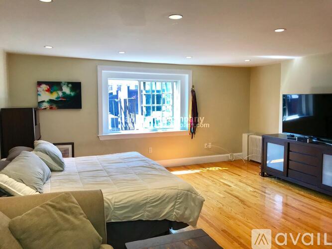 A bedroom with a large bed and a window overlooking a cityscape.