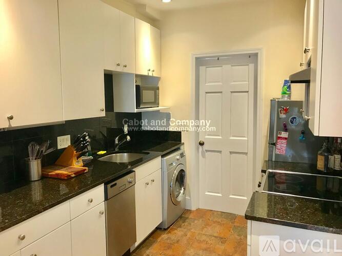 A kitchen with white cabinets and black countertops.