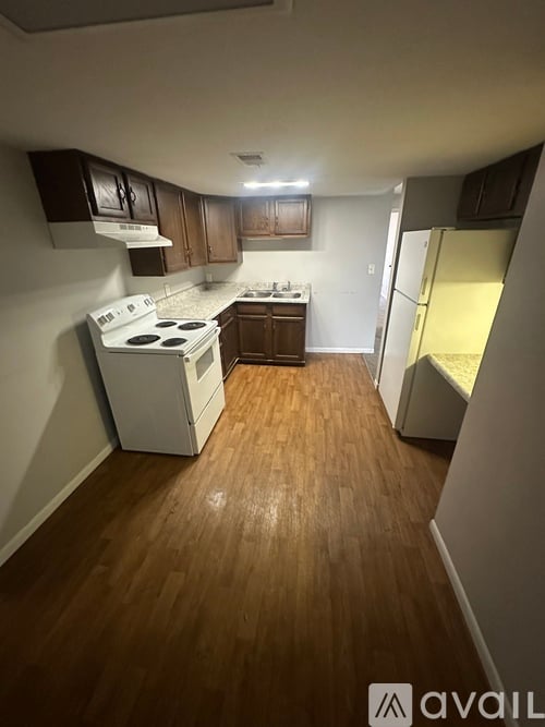 A kitchen with wooden floors and white appliances.