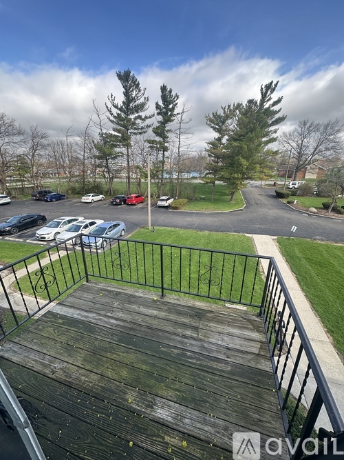 A wooden deck with a metal railing overlooks a parking lot.