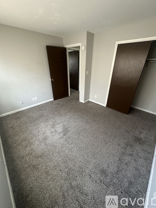 A room with a carpeted floor and two doors.