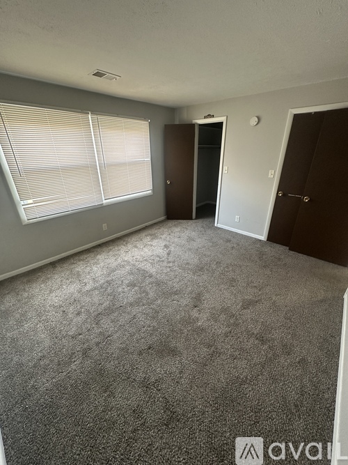 A room with a carpeted floor and a window with blinds.