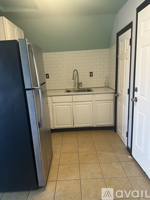 A kitchen with a black refrigerator and white cabinets.