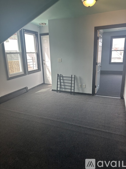 A room with a grey carpet and a black metal rack.