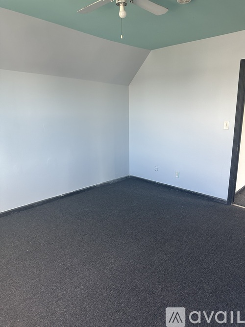 A room with a ceiling fan and a carpeted floor.
