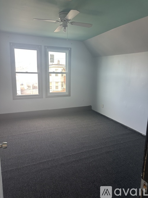 A room with a ceiling fan and carpeted floor.