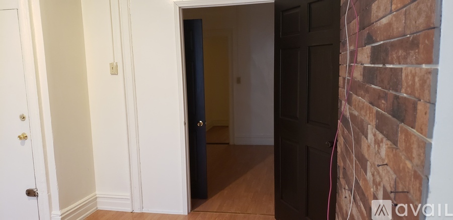 A hallway with a door at the end and a brick wall on the side.
