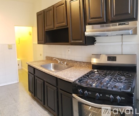 A kitchen with a black stove top oven and black cabinets.