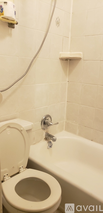 A white toilet in a bathroom with a white bathtub.
