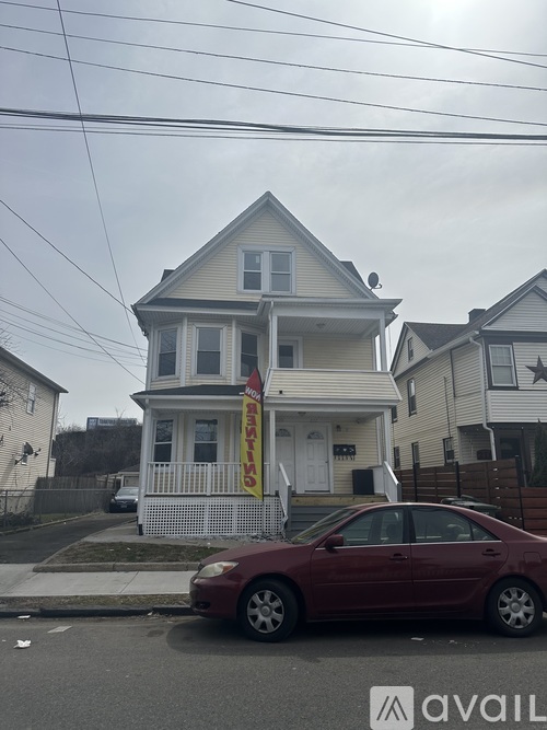 A two-story house with a red car parked in front.