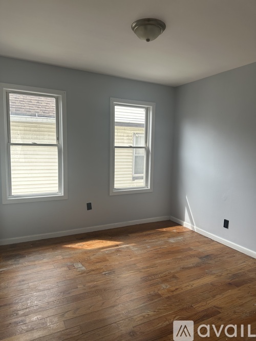 A room with wooden floors and two windows.