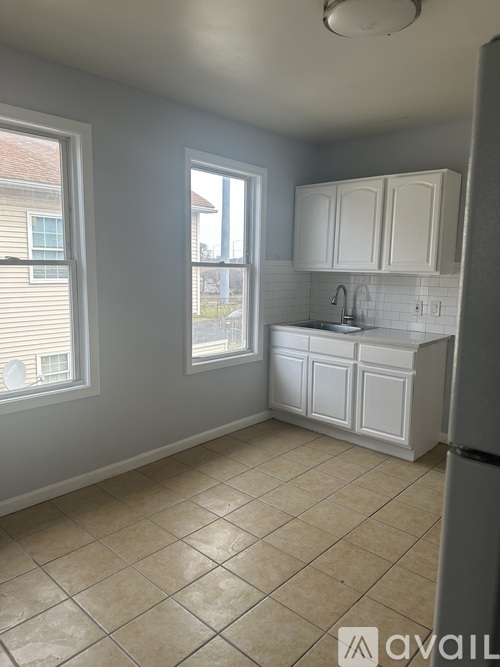 A kitchen with white cabinets and a tiled floor.