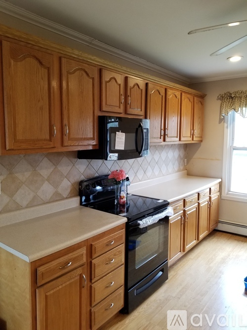 A kitchen with wooden cabinets and black appliances.