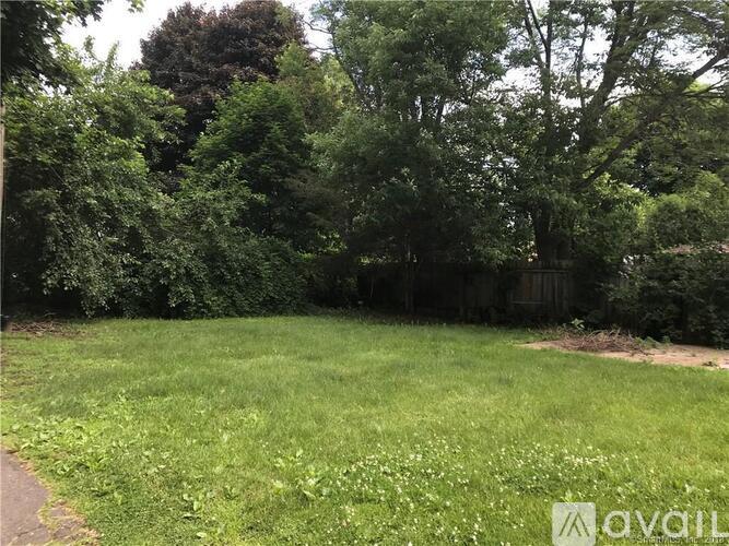 A grassy area with trees and a fence in the background.