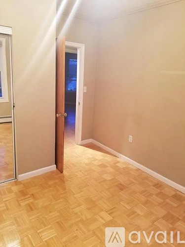 A hallway with a wooden floor and a door on the right.