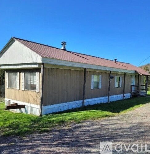 A brown house with a red roof and a white fence.