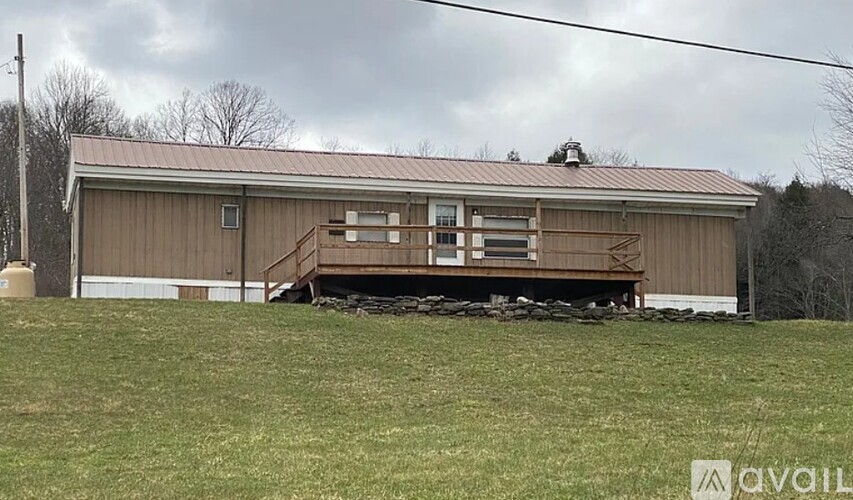 A large brown building with a metal roof and a deck in front.