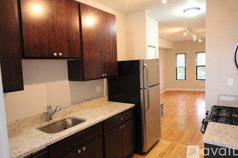 A kitchen with dark wood cabinets and a granite countertop.