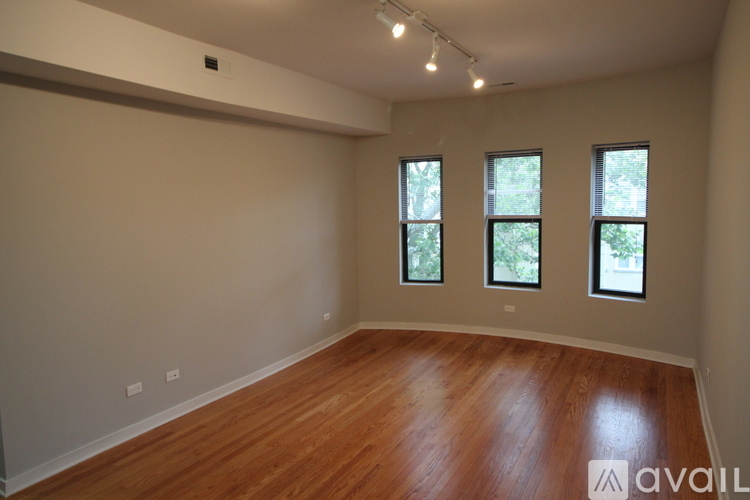 A room with wooden floors and three windows.