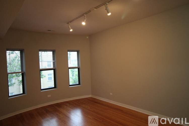 A room with wooden floors and three windows.