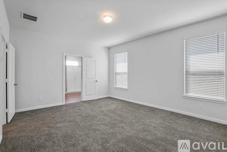 A spacious room with a carpeted floor and a window with blinds.