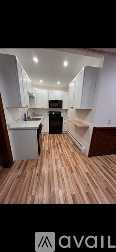 A kitchen with white cabinets and wooden flooring.